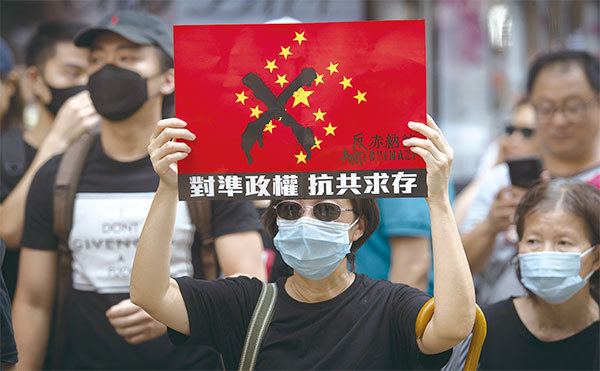 袁弓夷以72歲高齡挺身為港人發聲奔走,並以消滅共產黨為己任。圖為2019年10月1日中共竊政70年國殤日大遊行,港人高舉抗共標語。(AFP)