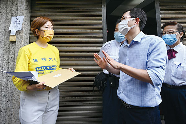 香港法輪佛學會會長梁珍遞信給《大公報》,但大公報大樓管理處人員,擺手表示大公報不接受信件。(宋碧龍/大紀元)