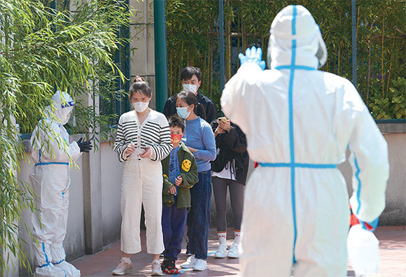 當局規定,每棟樓若出現陽性病例需再封鎖14天,並增加核酸測試,因而造成民眾之間的矛盾。圖為4月17日,在上海浦東區,居民排隊進行病毒測試。(LIU JIN / AFP)