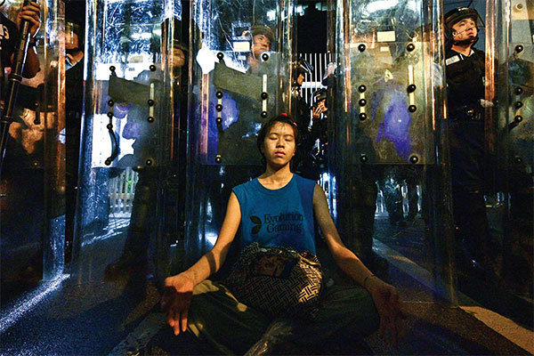 香港26歲的女孩林嘉露(Lam Ka Lo),6月11日晚間也前往港府總部金鐘區參與抗議,她靜坐在全副武裝的鎮暴警察盾牌前。(AFP)